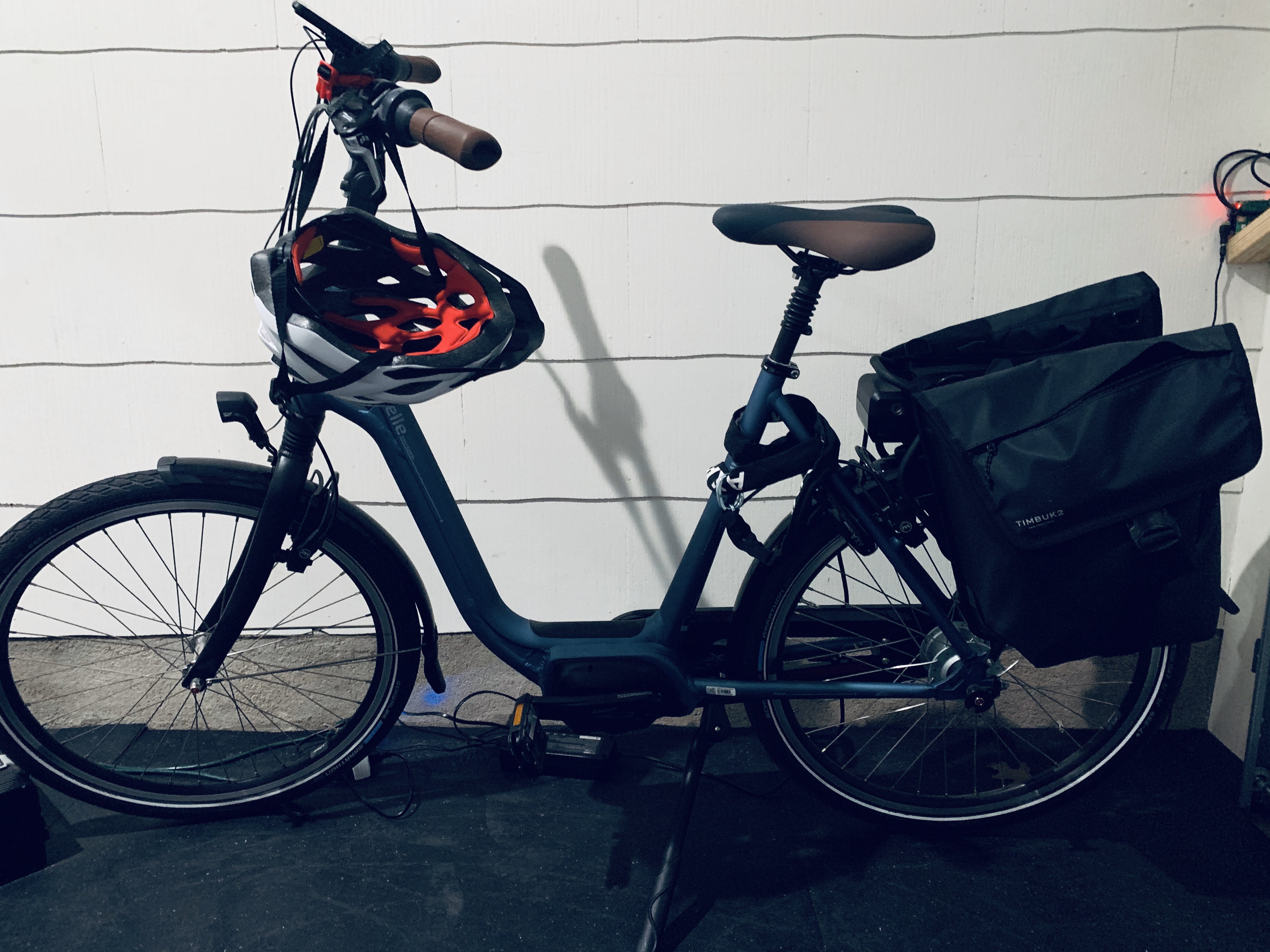 Gazelle electric bicycle parked in garage with helmet hanging from handlebars
